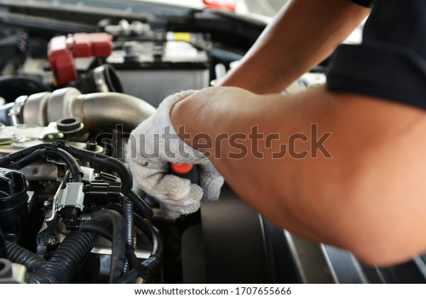Automotive mechanic working in garage. Repair\
service. Mechanic working on a diesel engine, close up. Technician\
hands of car mechanic in doing auto repair service and maintenance\
worker repairing.