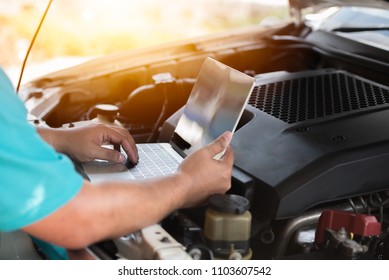 Automotive mechanical technician using laptop computer promgraming and investing by car diagnostic software, car maintenance service concept.
