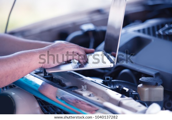 Automotive mechanical technician using laptop\
computer promgraming and  investing by car diagnostic software, car\
maintenance service\
concept.