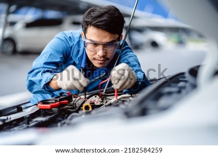 Automotive mechanics repairman use digital voltage multimeter to check voltage level in car battery, check the mileage of the car, auto maintenance service concept.