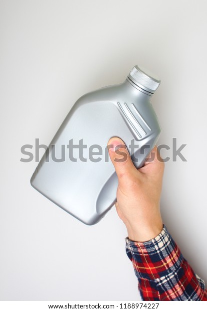 automotive oil in a hand a gray bottle on a\
light background