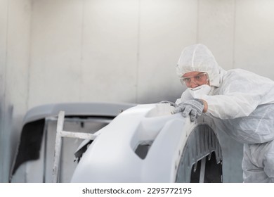 Automotive paint service concept. Male car mechanic inspecting quality of auto body after painting in automotive paint service shop. Automobile painter checking car frame in chamber - Powered by Shutterstock