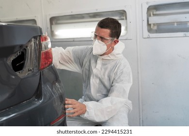 Automotive paint services, quality auto body shop concept. Male car mechanic inspecting quality auto body in automotive paint service shop. Technician checking, cleaning before painting car frame body - Powered by Shutterstock