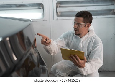 Automotive paint services, quality auto body shop concept. Male car mechanic inspecting quality auto body in automotive paint service shop. Technician checking, cleaning before painting car frame body - Powered by Shutterstock