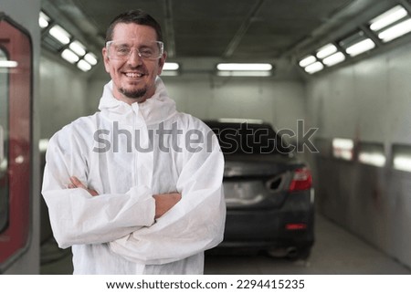 Automotive paint services and quality auto body shop concept. Male car mechanic working and standing with crossed arm in automotive paint service shop with happy and smile