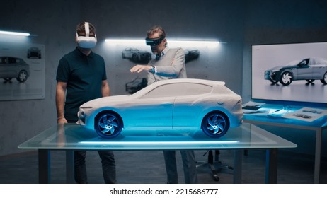 Automotive Professional Engineers With VR Headset And Joysticks Talk About Vehicle Production While Standing Infront Of A Prototypecar Model In A High Tech Office. Car Design Analysis And Improvement.