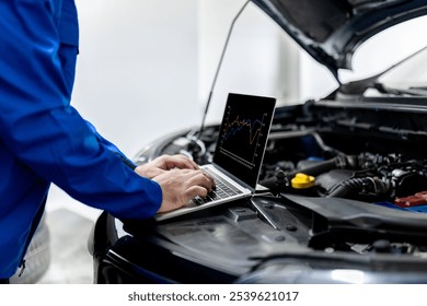 An automotive technician analyzes engine performance data on a laptop placed on the hood of a car in a well-lit workshop during the day. - Powered by Shutterstock