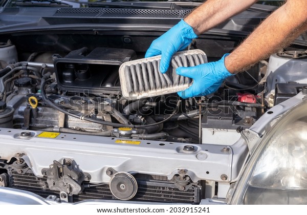 Automotive technician holding used dirty engine air\
filter for a car