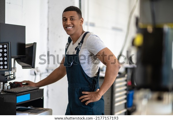 Automotive technician posing for the camera at\
the service station