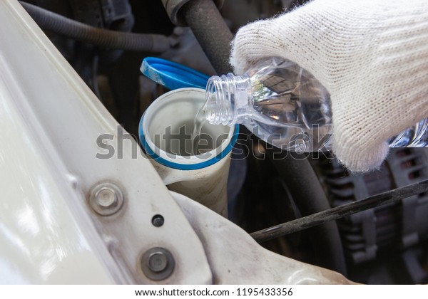 Automotive Technician working\
check system water and fill Injection water for glass into car\
engine  