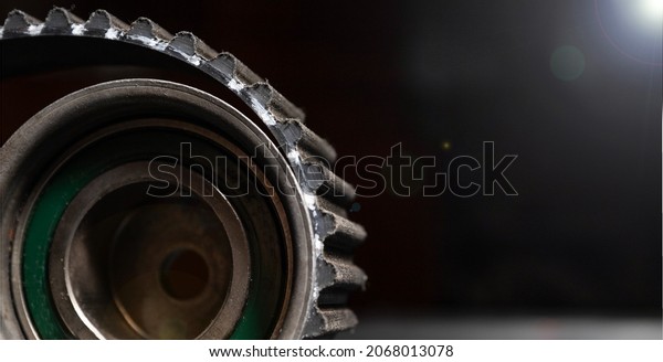 automotive timing belt on a\
black background. Replacement concept for idler pulleys and engine\
belts.