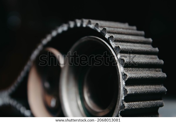 automotive timing belt on a\
black background. Replacement concept for idler pulleys and engine\
belts.