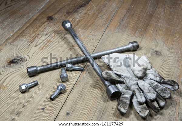 automotive tool - screwdriver for changing tires\
and dirty gloves on wooden\
floor