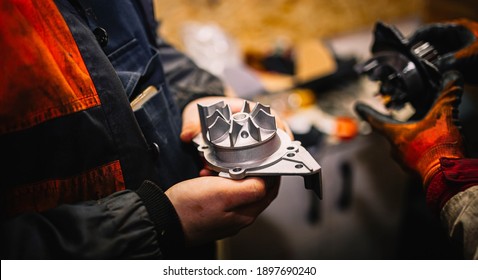 Automotive water pump of the engine cooling system in the hands of an auto mechanic, replacement of the pump with a metal impeller.