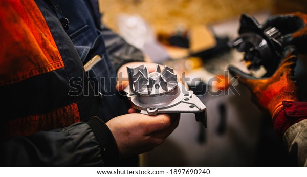 Automotive water pump of the engine cooling\
system in the hands of an auto mechanic, replacement of the pump\
with a metal\
impeller.