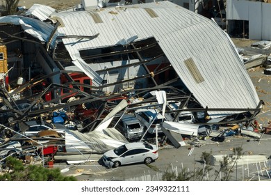 Automotive workshop destroyed by hurricane wind with damaged cars under ruins in Florida. Consequence of natural disaster