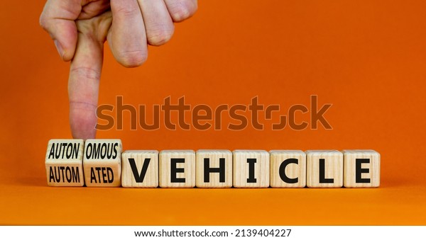 Autonomous or automated vehicle symbol.\
Businessman turn cubes changes words Automated vehicle to\
Autonomous vehicle. Orange background. Business Autonomous or\
automated vehicle concept, copy\
space.