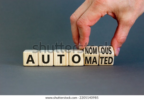 Autonomous or automated vehicle symbol.\
Businessman turns cubes and changes words Autonomous to Automated.\
Grey background. Business technology autonomous or automated\
vehicle concept. Copy\
space.