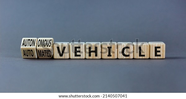 Autonomous or automated vehicle symbol. Turned\
wooden cubes and changed words Automated vehicle to Autonomous\
vehicle. Grey background. Business Autonomous or automated vehicle\
concept, copy space.