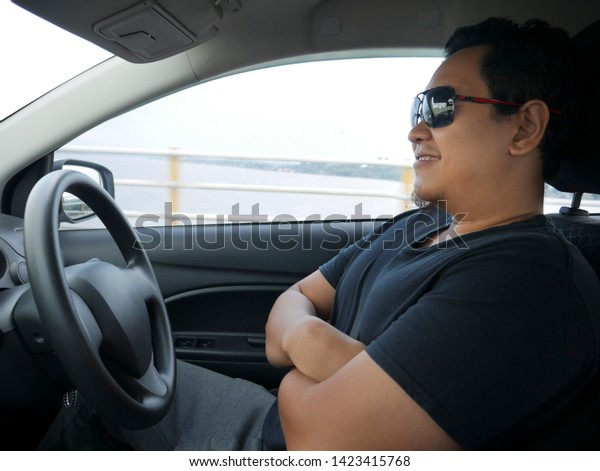 Autonomous or self driving car\
concept, Asian male smiling in his self-driving car, autopilot\
mode