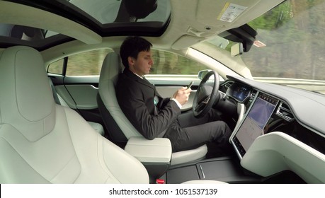 AUTONOMOUS TESLA CAR, FEBRUARY 2016:  Businessman On Business Trip Traveling In New Luxury Autonomous Self-driving Autopilot Tesla Model S Driverless Car. Electric Vehicle Driving On Highway By Itself