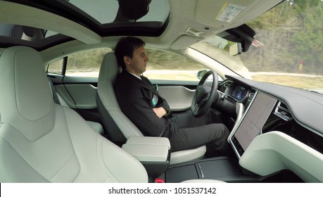 AUTONOMOUS TESLA CAR, FEBRUARY 2016:  Businessman On Business Trip Traveling In New Luxury Autonomous Self-driving Autopilot Tesla Model S Driverless Car. Electric Vehicle Driving On Highway By Itself