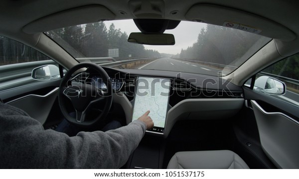 AUTONOMOUS TESLA CAR, FEBRUARY 2016:  Tesla autopilot\
self-driving in severe weather condition with no human\
intervention. Driver browsing the internet using touchscreen in\
futuristic autonomous\
car