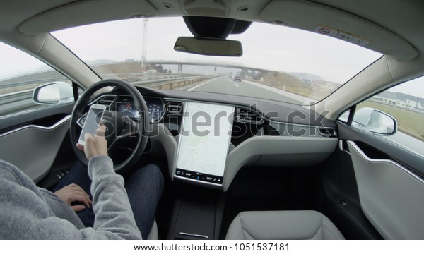 AUTONOMOUS TESLA CAR, FEBRUARY 2016:  Tesla Model\
S autonomous electric car autopilot self-driving in bad weather\
condition on highway with no human intervention. Driver texting on\
mobile device
