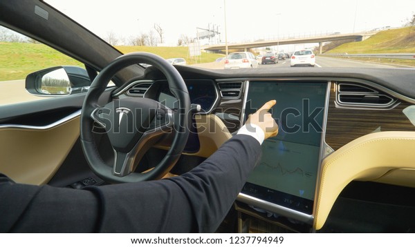 AUTONOMOUS TESLA CAR, MARCH 2018 - CLOSE UP:\
Unrecognizable stylish woman setting up the navigation on the\
touchscreen console in her autonomous car. Businesswoman swiping\
her fingers across\
display.
