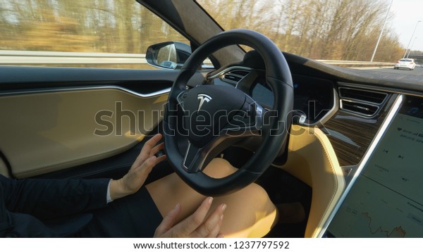 AUTONOMOUS TESLA CAR, MARCH 2018 - CLOSE UP: Well\
dressed woman lifts her hands up to adjust the self driving car\
speeding down the highway. Startled female thinks of grabbing the\
car’s steering wheel