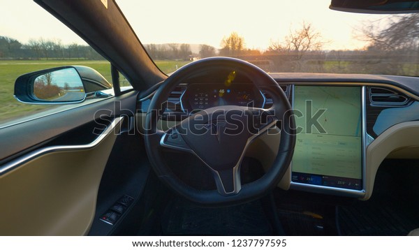 AUTONOMOUS TESLA CAR, MARCH 2018 – SUN FLARE: Golden\
evening sun rays shine through the windshield of an autonomous car\
cruising through idyllic countryside. Interior of awesome self\
navigating car.
