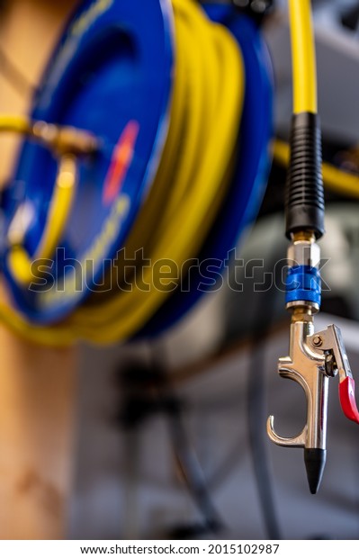 auto-rewinding air hose reel with coiled tubing\
mounted on a wall in a\
shop