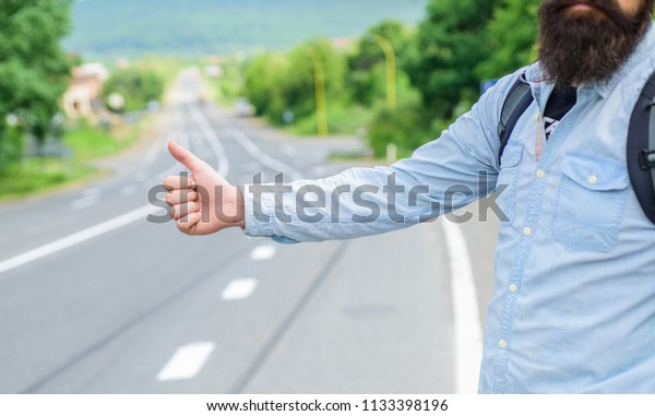 Autostop travel. Pick me up. Thumb up gesture try\
stop car road background. Hand gesture hitchhiking. Make sure you\
know right gestures to stop car. Thumb up sign not work in many\
parts of world.