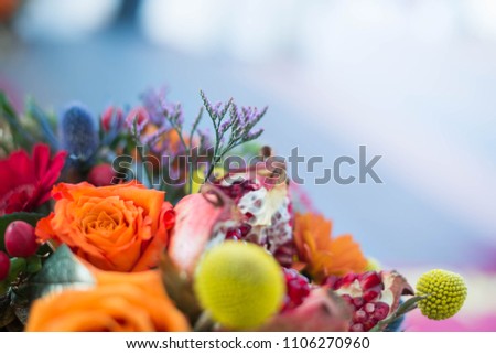 Autum bouquet of leaves, orange and yellow flowers, berries and pomegranate. Close up.