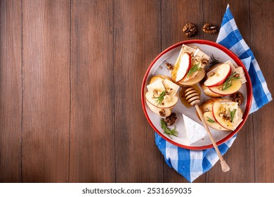 Autumn Apple Brie Crostini with Walnuts and Honey, Fall dinner, Thanksgiving party appetizers idea. Small sandwiches with red apple slices, brie cheese and sweet honey drizzles - Powered by Shutterstock