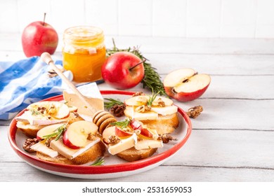 Autumn Apple Brie Crostini with Walnuts and Honey, Fall dinner, Thanksgiving party appetizers idea. Small sandwiches with red apple slices, brie cheese and sweet honey drizzles - Powered by Shutterstock