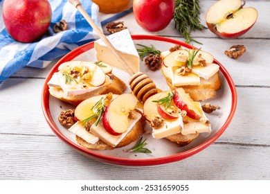 Autumn Apple Brie Crostini with Walnuts and Honey, Fall dinner, Thanksgiving party appetizers idea. Small sandwiches with red apple slices, brie cheese and sweet honey drizzles - Powered by Shutterstock