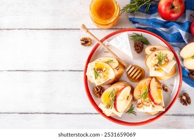 Autumn Apple Brie Crostini with Walnuts and Honey, Fall dinner, Thanksgiving party appetizers idea. Small sandwiches with red apple slices, brie cheese and sweet honey drizzles - Powered by Shutterstock