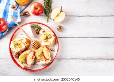 Autumn Apple Brie Crostini with Walnuts and Honey, Fall dinner, Thanksgiving party appetizers idea. Small sandwiches with red apple slices, brie cheese and sweet honey drizzles - Powered by Shutterstock