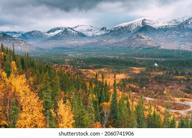 Autumn arctic landscape. View of the misty snow-capped mountains and autumn colorful forest and tundra in the Arctic,Kola Peninsula. Mountain hikes and adventures. Austere, cold atmosphere. 