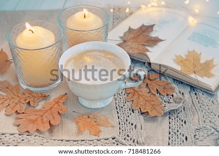 autumn background. Cup of coffee, candles, book and autumnal leaves on table close up. cozy still life. home comfort in fall season. relax time