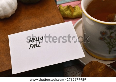 autumn background - hello fall write on card with rustical wooden background 