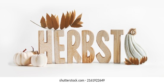 Autumn background with wooden letters writing word herbst in German, pumpkins and leaves at white backdrop. Seasonal fall setting. Front view.