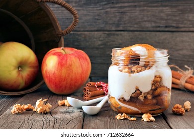 Autumn Baked Apple Parfait With Caramel Sauce In A Mason Jar, Still Life On A Rustic Wood Background