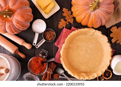 Autumn Baking Table Scene With Pumpkin Pie Ingredients. Overhead View On A Dark Wood Background.