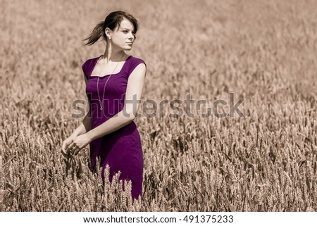 Autumn beauty in cornfield with purple dress. Beautiful young woman with pretty loud dress in a wide field of corn