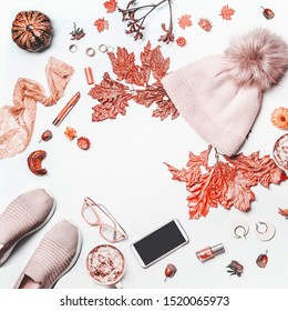 Autumn Beauty Feminine Arrangement On White Background With Knit Hat With Pom Pom,pumpkin. Sneakers, Smartphone With Mock Up , Fall Leaves, Cosmetics And Mug With Hot Chocolate. Top View. Flat Lay.  