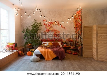 Autumn bedroom, living room interior. Red and yellow leaves and flowers in the vase and pumpkin on light background.
