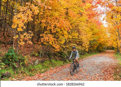 Autumn biking happy woman traveling on road bike through foliage path in nature forest outdoors. Canada fall travel destination.