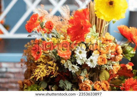Autumn bouquet of yellow and orange flowers. Beautiful floral arrangement with fall orange and red flowers and berries, closeup. Cozy Interior fall decor with Autumn composition plants at home. 